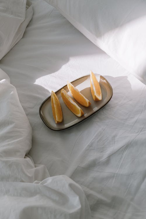 Sliced Orange Fruit on a Plate on White Textile