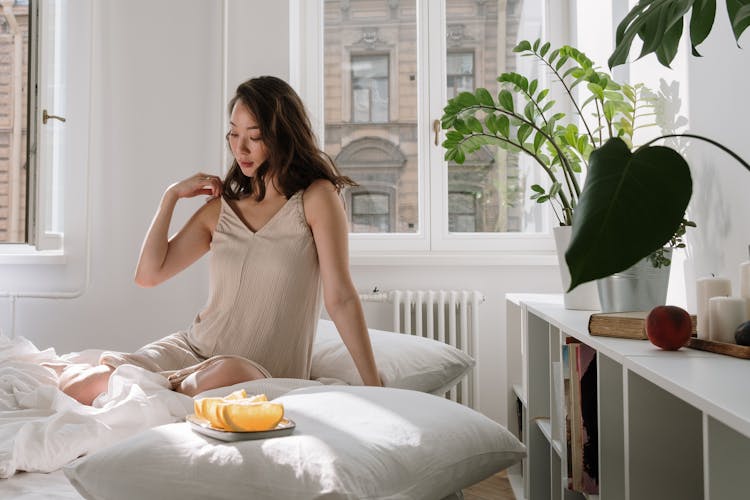 Woman In Nightgown Sitting On A Bed 