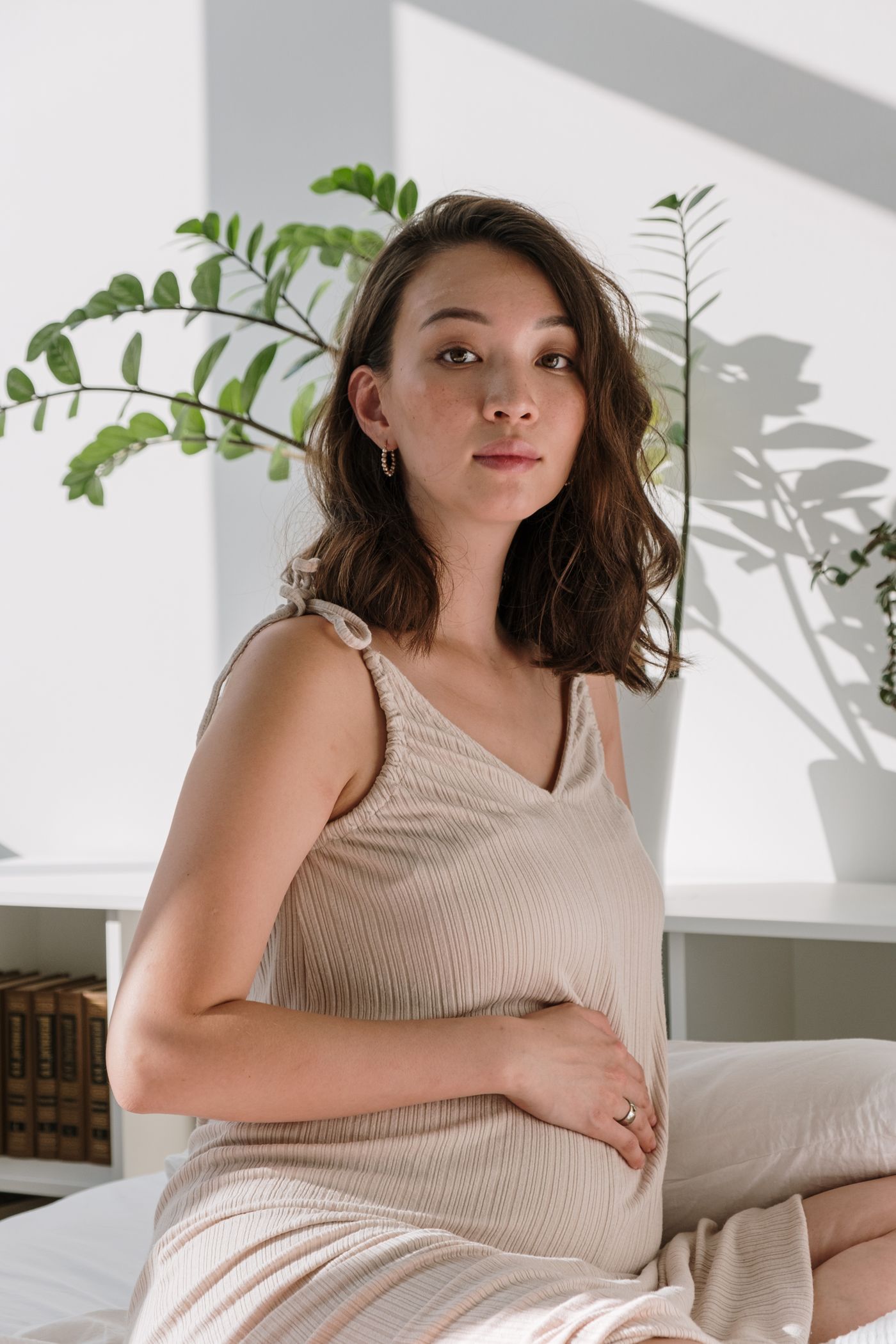 Femme enceinte en tenue confortable se reposant dans une chambre aux couleurs naturelles