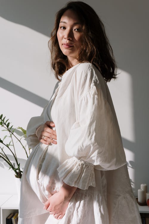 Free Woman in White Long Sleeve Dress Showing Baby Bump Stock Photo