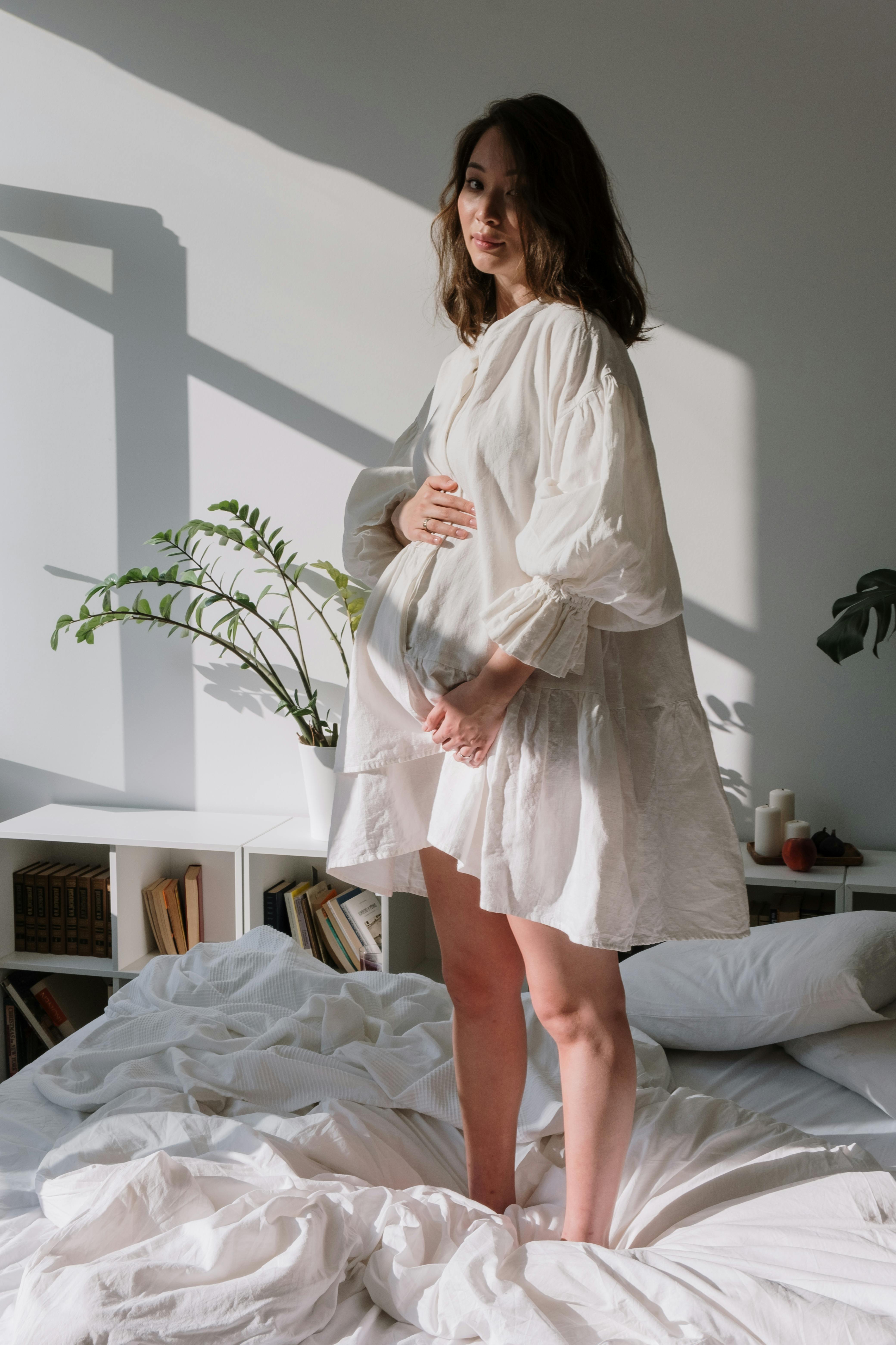 a pregnant woman standing on bed