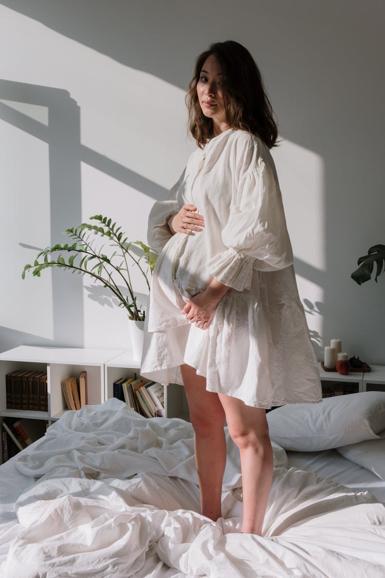 A Pregnant Woman Standing On Bed