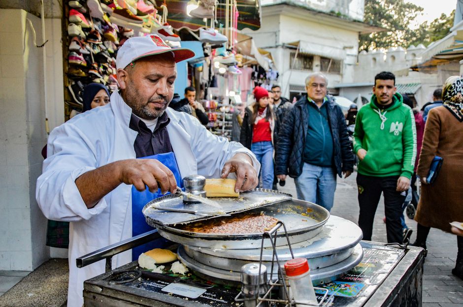 A street vendor prepares food in the bustling market of Tangier, Morocco.