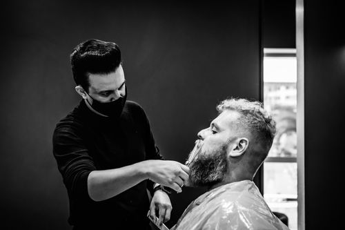 Free A barber skillfully trims a client's beard in a modern salon. Stock Photo