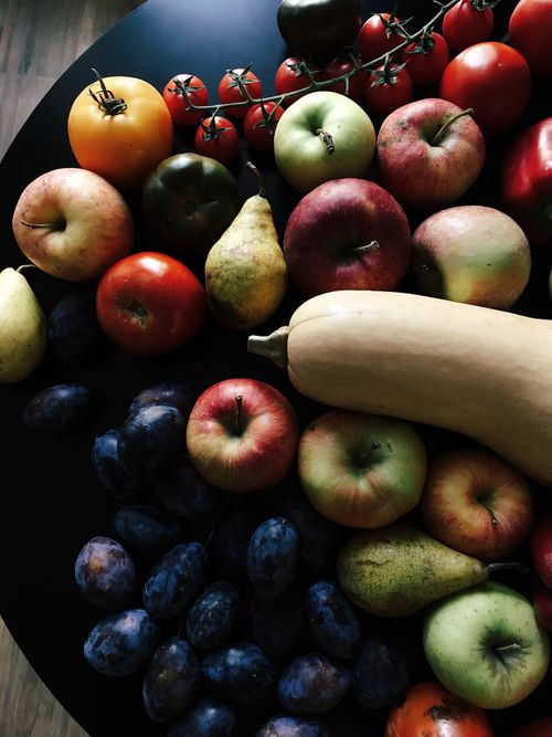 Free A vibrant display of fruits and vegetables including apples, pears, and tomatoes on a dark surface. Stock Photo