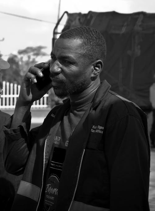 A Grayscale Photo of a Man Talking on the Phone
