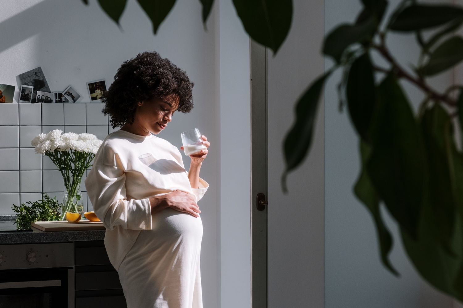 Femme enceinte buvant un verre d’eau dans une cuisine lumineuse