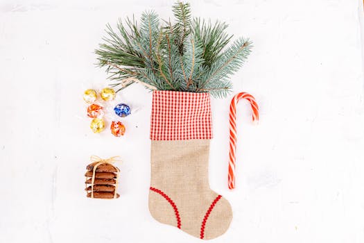 A festive Christmas stocking filled with pine branches, candy canes, cookies, and chocolates on a white background.