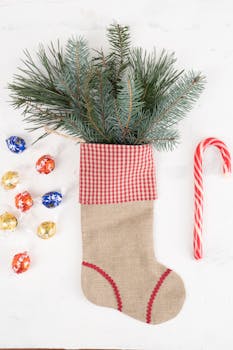 Holiday-themed Christmas stocking with pine branches and candy on white background.