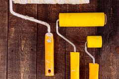 Top view of yellow paint rollers arranged on a wooden table for DIY projects.