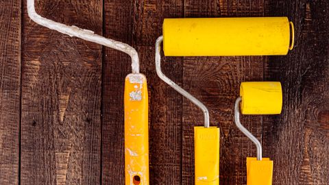 Top view of yellow paint rollers arranged on a wooden table for DIY projects.