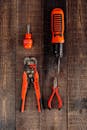 Electric Screwdriver and Pliers on Wooden Surface