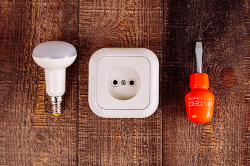 An Outlet Screwdriver and a Lightbulb on a Wooden Surface