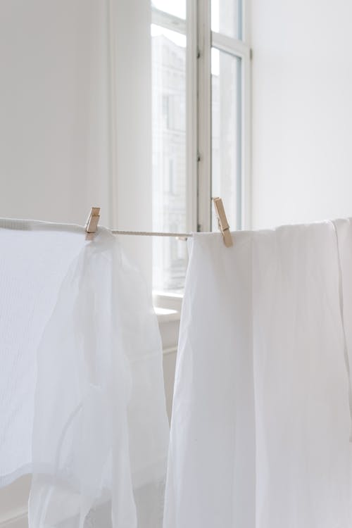 Белый текстиль на коричневой вешалке для одежды