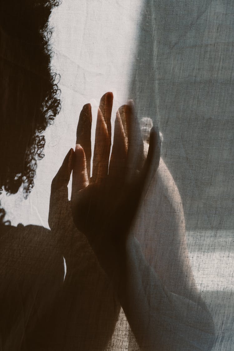 Shadow Of A Woman Touching A Wall With Her Hand