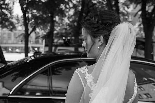 Woman Wearing Wedding Veil Facing Car