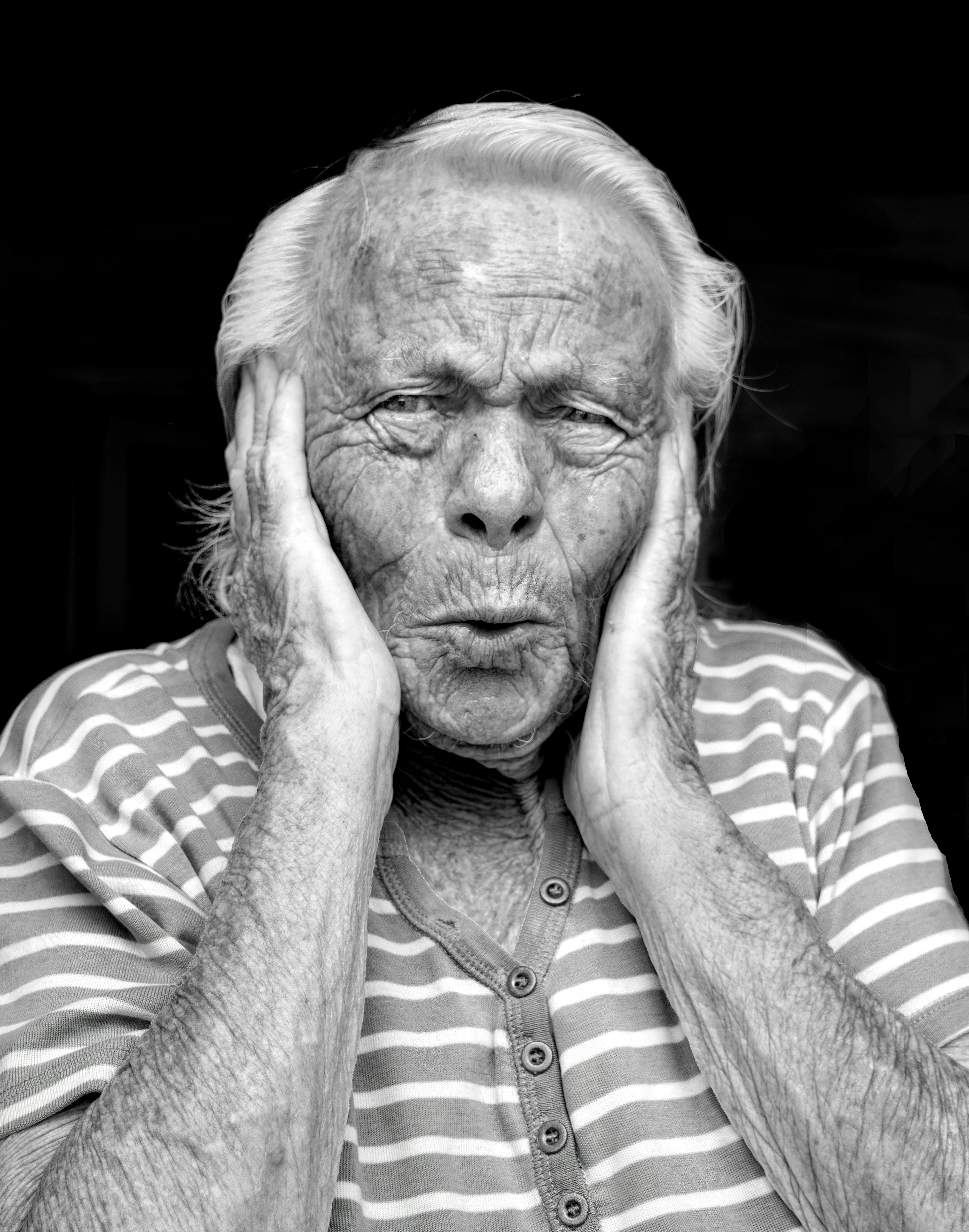 A striking black and white portrait of a senior woman making a funny face.