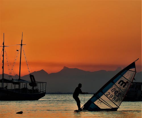 Windsurfer and a Boat in Sea at Sunset
