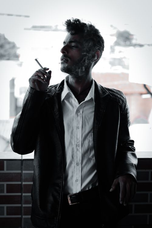 Free Dramatic portrait of a man smoking indoors, highlighting personal vices and lifestyle choices. Stock Photo