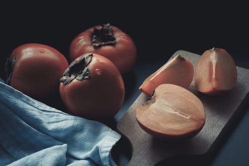 Free Sliced Persimmon Fruit on a Wooden Chopping Board Stock Photo