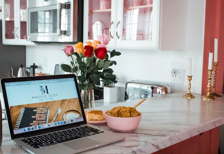 A Laptop Beside A Bowl Of Rice Meal On Kitchen Countertop