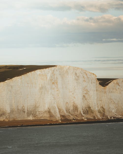 Rocky cliff against cloudy sky