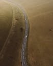 Aerial view of straight paved roadway with marking lines running between meadow covered with grass in countryside in nature outside