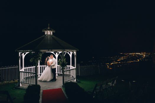 Bride and Groom Standing in an Illuminated Gazebo at Night 