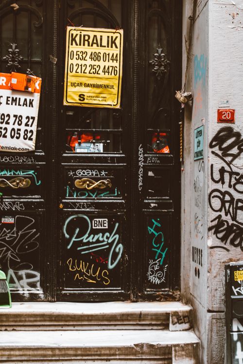 Free A vintage wooden door with graffiti and signage in an urban setting. Stock Photo