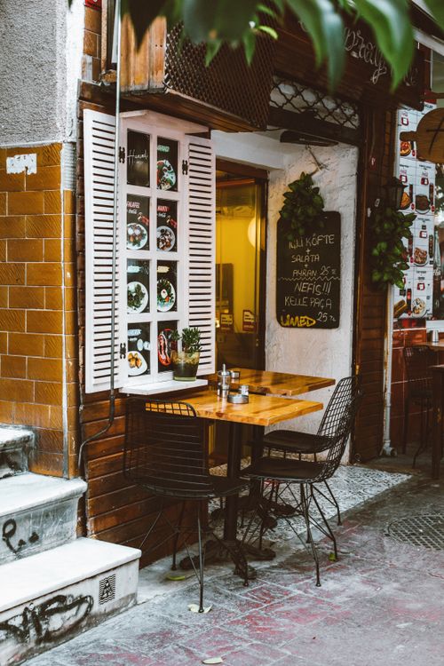 Free Charming urban café with outdoor seating, inviting atmosphere, and decorative menu display. Stock Photo