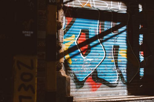 Free Vibrant urban graffiti art on a garage door under sunlight and shadow. Stock Photo