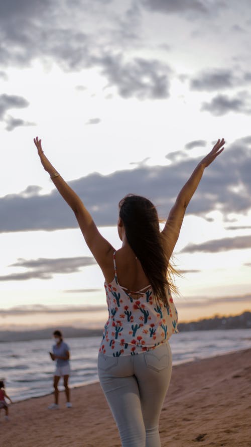 Free Woman with Raised Arms on Beach Stock Photo