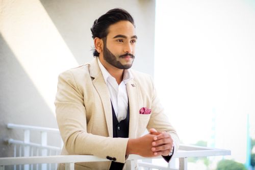 Free A poised man in a beige suit stands on a balcony, exuding elegance and sophistication. Stock Photo