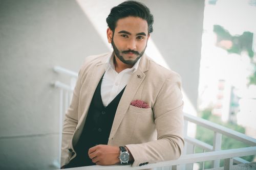 Free A well-dressed man in elegant formalwear posing confidently on a balcony. Stock Photo