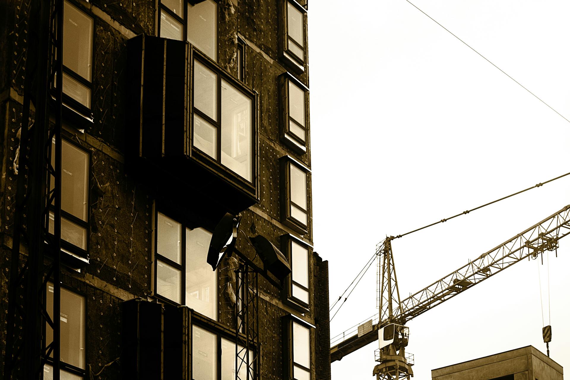Sepia-toned image of a construction site with a building facade and crane.