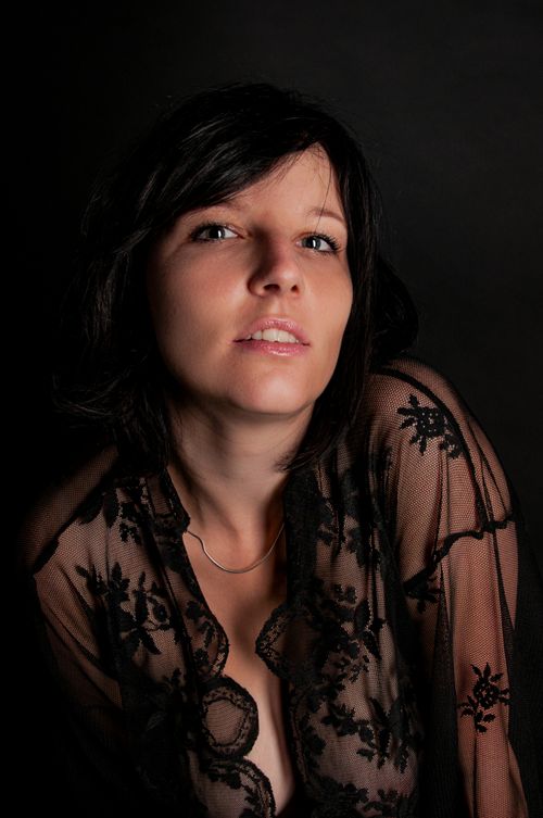 Free Elegant portrait of a woman in lace blouse with a dark background, showcasing beauty and fashion. Stock Photo