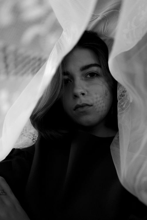Free Black and white of charming female with veil on head looking at camera while standing under light Stock Photo