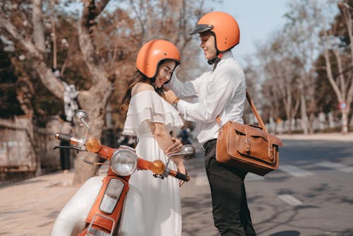 Man in White Long Sleeve Shirt Wearing Orange Helmet Standing Beside a Woman in White Dress