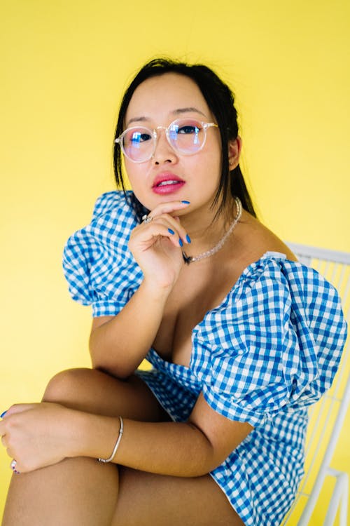 Woman in Blue and White Checkered Dress Shirt Wearing White Framed Eyeglasses on Yellow Background