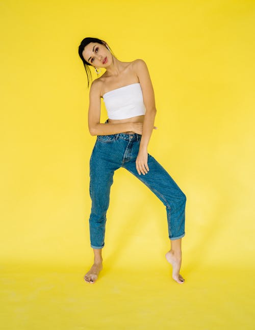 A Woman in White Tube Top and Denim Jeans Posing