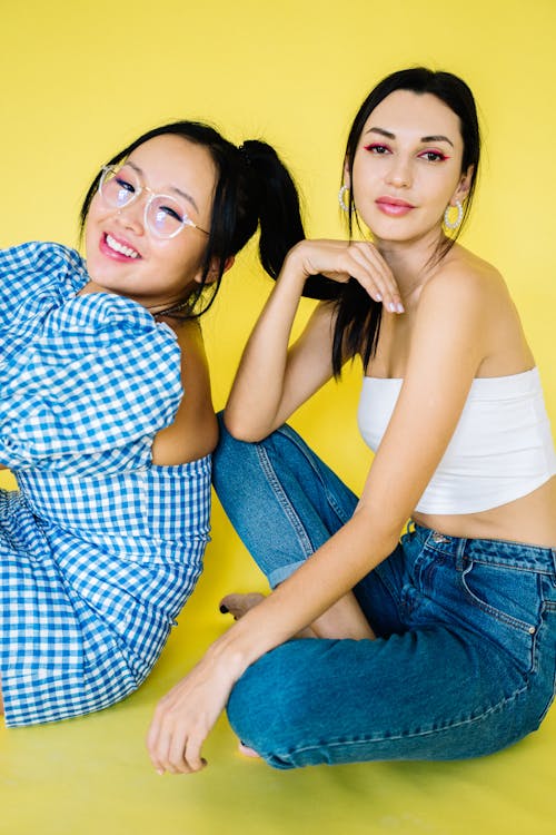 Wanita Dengan Tank Top Putih Dan Jeans Denim Biru Duduk Di Sofa Kuning