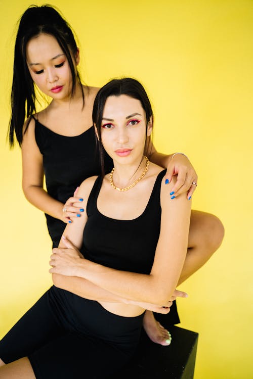 Two Brunette Women in Black Clothing Posing in a Studio