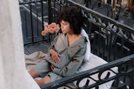 一幅宁静的孕妇肖像，坐在城市舒适的阳台上，附近有鲜花