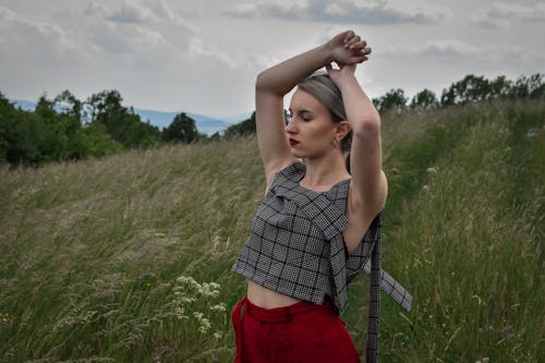 Blond Woman Standing on a Field with Arms Raised 