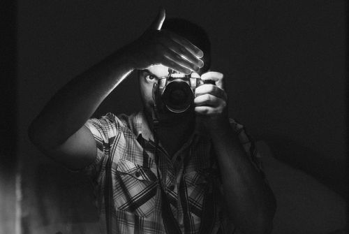Free Artistic black and white selfie of a man using a DSLR camera, partially obscured by hand. Stock Photo
