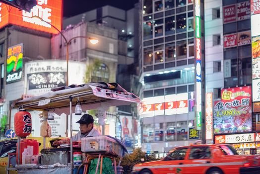 Vibrant Tokyo street scene with a food vendor under neon lights capturing urban night life.