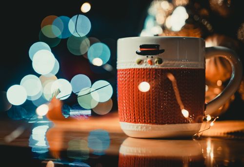Free A cozy snowman-themed mug with warm holiday lighting and festive bokeh background. Stock Photo