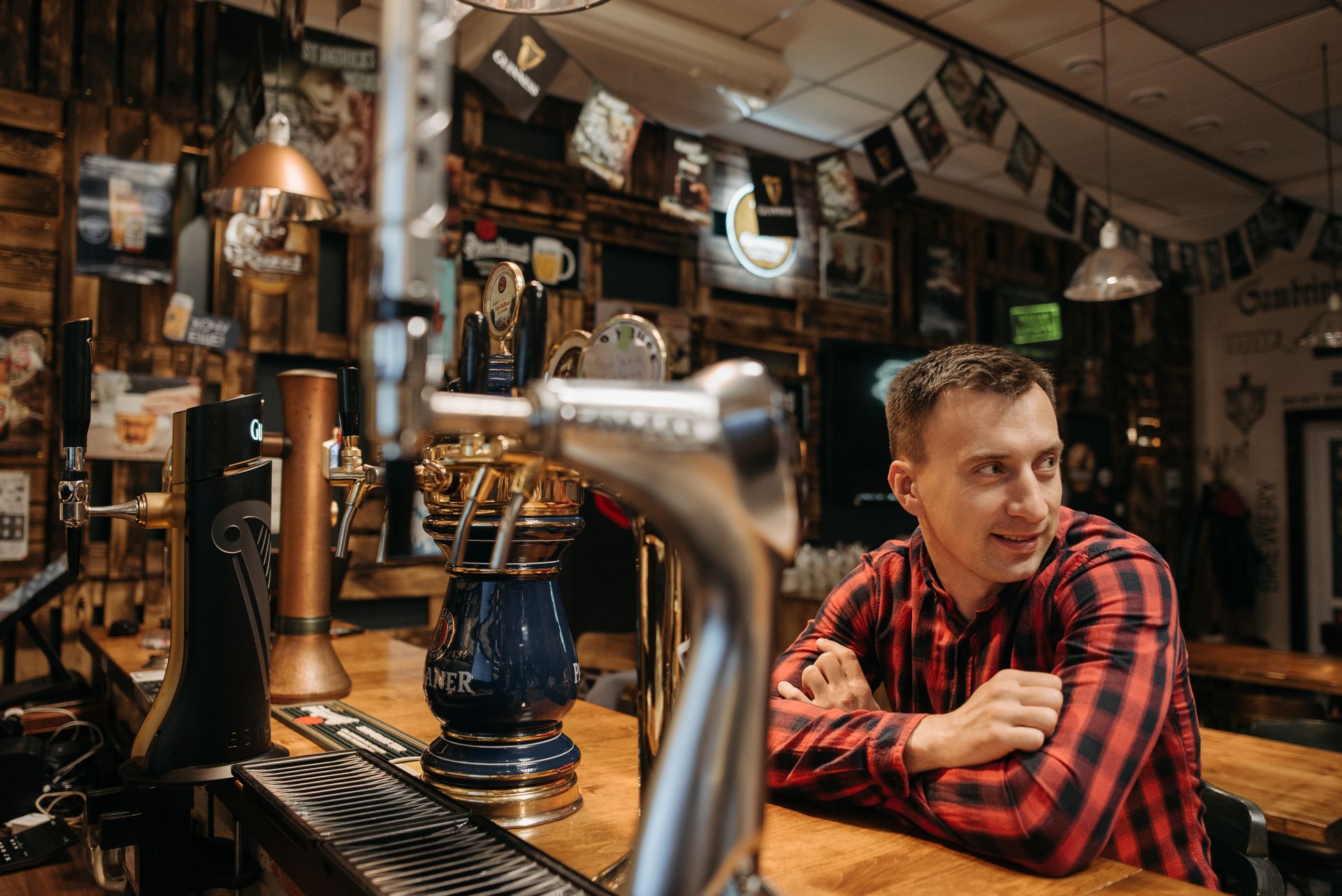 Man in Check Shirt Leaning on Wooden Bar Counter