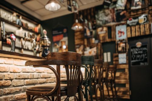 Free Warm, inviting pub interior featuring rustic wooden chairs in a laid-back setting. Stock Photo