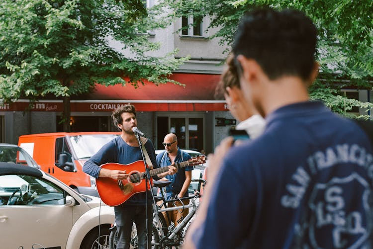 Man Playing Guitar And Singing On Street